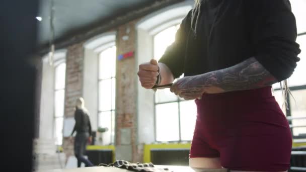 Сильная спортсменка надевает спортивные бинты на руки — стоковое видео