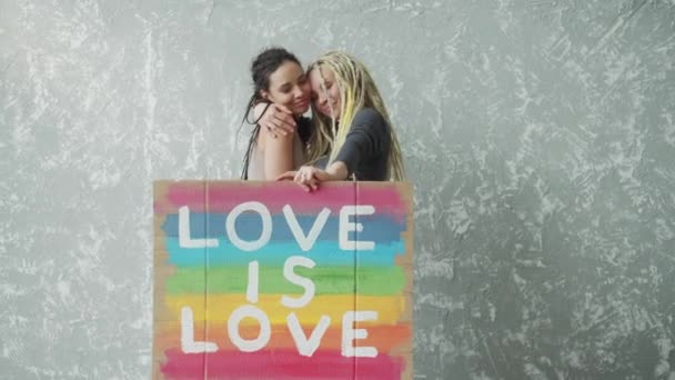Pareja lesbiana femenina sosteniendo cartel LGBT colorido — Vídeo de stock