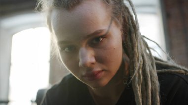 Güçlü bir sporcu kadın kutunun üzerinde oturuyor ve kameraya bakıyor.