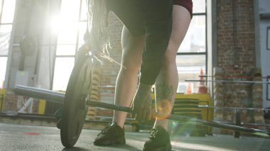 A strong athletic woman is preparing a barbell for her workout