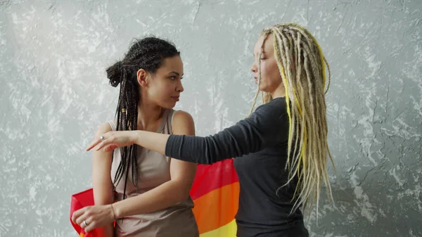 Een meisje bedekt haar vriendin met een LGBTQ vlag en trekt dan aan zichzelf — Stockfoto