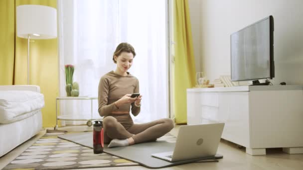 Una chica atractiva está viendo algo en un teléfono y sonriendo — Vídeos de Stock