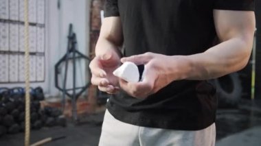 Güçlü bir atletik adam egzersiz için elini tebeşirliyor. 