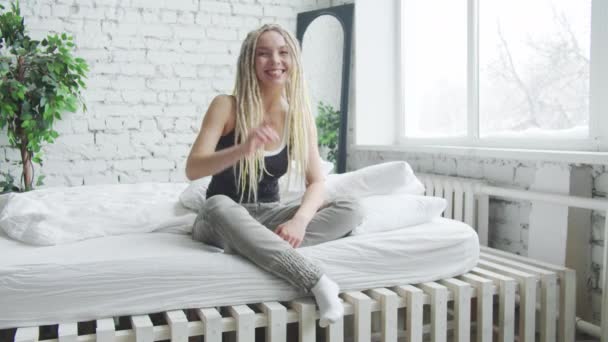 Femme blonde portant un débardeur noir et un pantalon confortable accueille dans sa chambre — Video