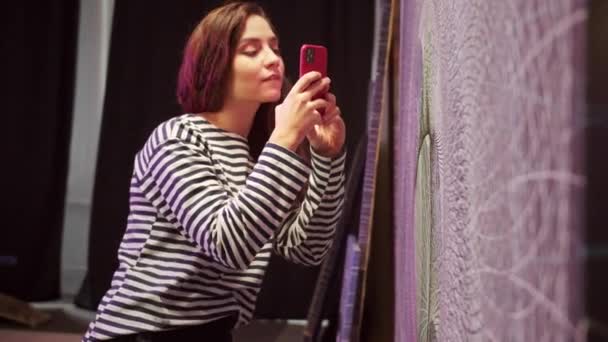 Una chica atractiva está tomando una foto de una foto terminada — Vídeo de stock