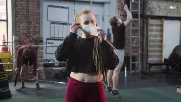 Сильная атлетическая женщина надевает маску и скрещивает руки — стоковое видео
