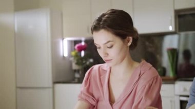 Kocası kitap okurken genç bir kadın dizüstü bilgisayarda bir şeyler yazıyor.