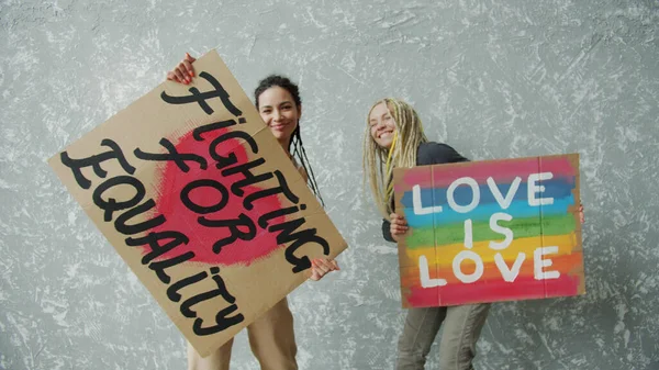 Rastalı genç kızlar LGBTQ posterleri taşımaktan mutlu olurlar. — Stok fotoğraf