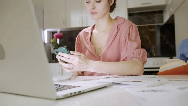 Una mujer joven está escribiendo algo en el portátil mientras su marido está leyendo un libro — Foto de Stock