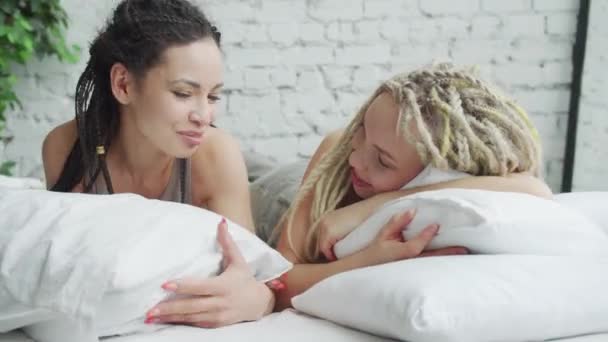 Mosolygó lányok fekszenek a párnákon, nézik egymást. — Stock videók