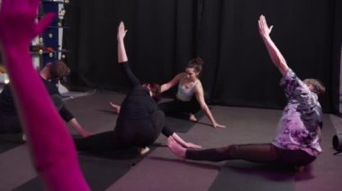 Genç sporcu kadın grupla yoga yapıyor, Yarım Lotus Parmak Dengesi egzersizi yapıyor.