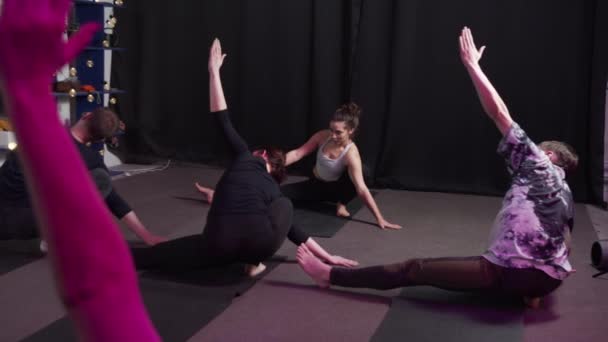 Fiatal sportos nő gyakorló jóga csoport, csinál Half Lotus Toe Balance gyakorlat — Stock videók