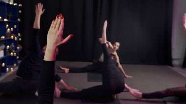 Grup, kollarını havada tutarak yoga yapıyor.