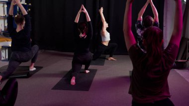 Küçük bir grup insan yoga sınıfında sorunsuz ve yavaş hareket ediyor.