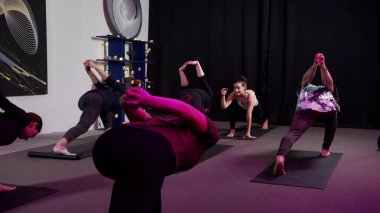 Arkalarında kilitli bir el ile esneme hareketleri yapan genç bir grup.