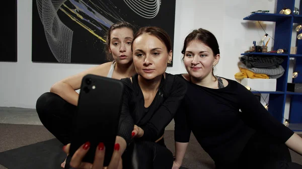 Tres chicas sonrientes haciendo videollamada con un amigo sentado en alfombras — Foto de Stock