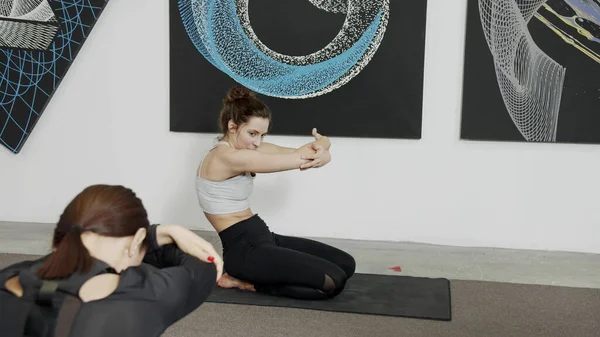 Siyah minderler üzerinde yoga yapan genç kadınlar.