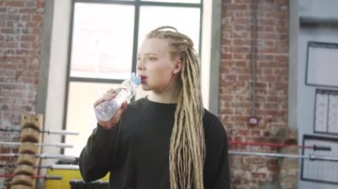 A strong sportswoman is crossing and drinking water