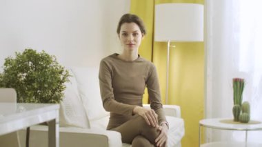 Genç bir kadın kameraya bakıyor ve gülümsüyor. 