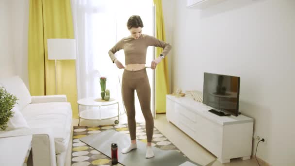 A sporty woman is taking measurements of her waist — Stock Video