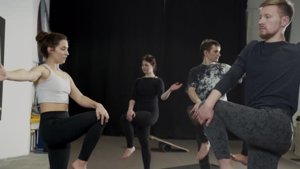 Красивые женщины и мужчины, занимающиеся йогой для поддержания равновесия на ногах — стоковое видео