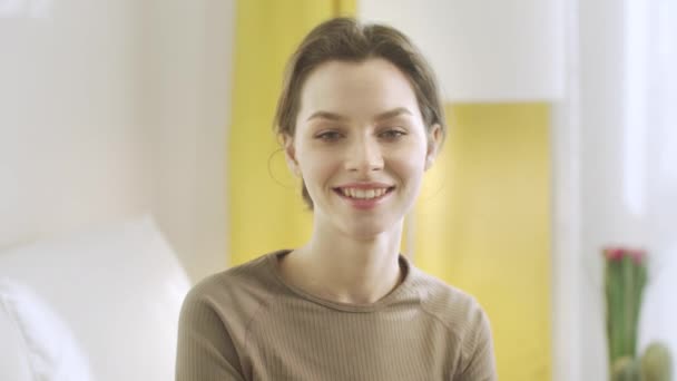 En ung kvinna tittar in i kameran och ler — Stockvideo
