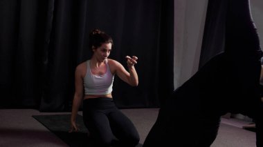 Kız, karanlık bir odada minderin üzerinde yoga pozu veriyor.