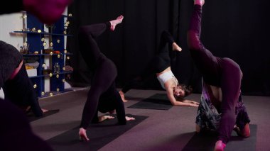 Eğitmenli bir grup genç sporcu fitness sınıfında yerde aerobik yapıyor.