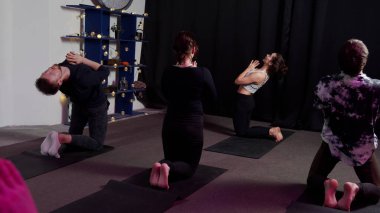 Bir grup yogi spor stüdyosunda yoga sırasında sorunsuzca ilerler.