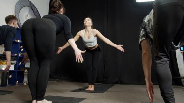 Koyu renk minderler üzerine grup yoga eğitimi.