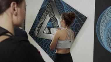Büyük resmin yanında duran bir grup insanla birlikte yoga eğitmeni.