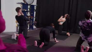 Bir grup yogi spor stüdyosunda yoga sırasında sorunsuzca ilerler.