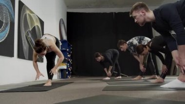 Bir grup acemi yogi antrenörden sonra egzersizi tekrarlamaya çalışır.