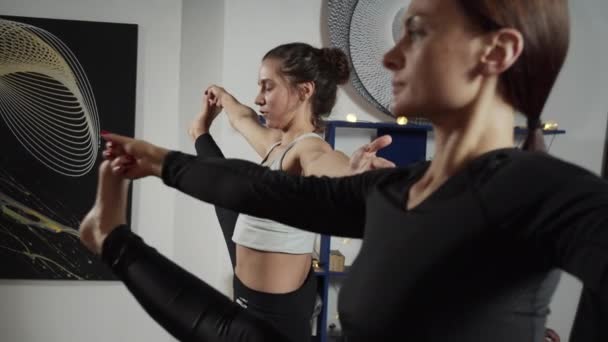 Genç, sportif kadınlar yoga yapıyorlar. Bir bacakları yukarıda, bir bacakları üzerinde duruyorlar. — Stok video