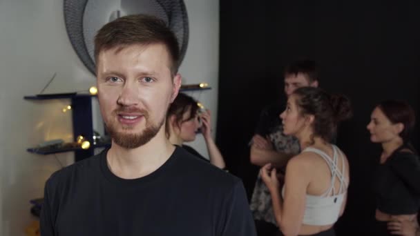 Tall bearded guy waving to the camera while people are chatting at the background — Stock Video