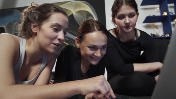 Chicas jóvenes tumbadas en esteras surgiendo a través de Internet sobre el yoga — Vídeos de Stock