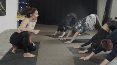 Yoga öğretmeni grubuna doğru kobra pozu vermede yardım ediyor.