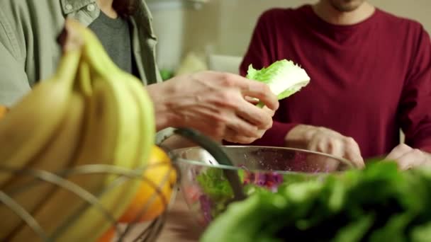 Två underbara män lagar sallad tillsammans. — Stockvideo