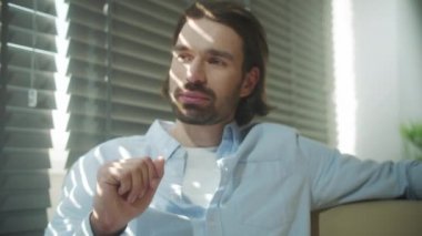 Genç bir iş adamı kanepede oturuyor ve meslektaşıyla konuşuyor.