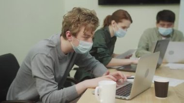 Meslektaşlar bir ofiste oturup birlikte çalışıyorlar.