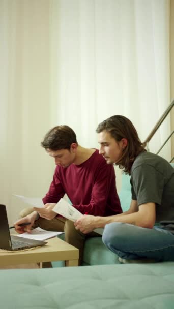 Twee vrienden zijn aan het werk en kijken door documenten — Stockvideo