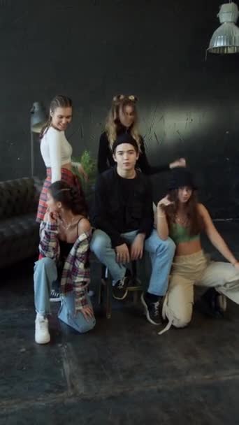 Teenagermädchen tanzen fröhlich um einen Typen in der Nähe einer schwarzen Wand — Stockvideo