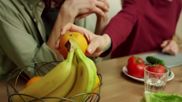 Un jeune homme met une orange dans le bol pendant la conversation — Video