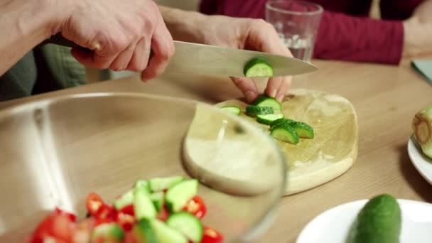 Een jongeman kookt een salade voor zijn vriend. — Stockvideo