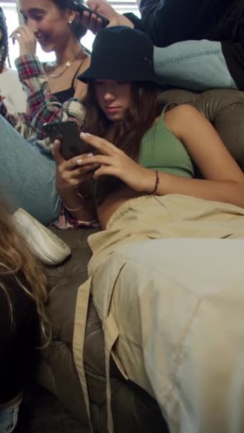 Junge Leute sitzen in Telefonen nebeneinander auf dem Sofa — Stockvideo