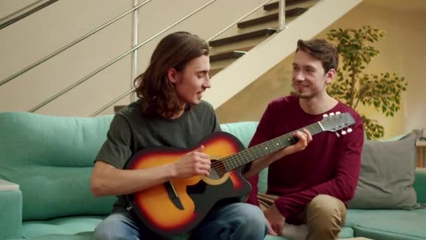 Egy fiatalember gitározik a barátjának. — Stock videók