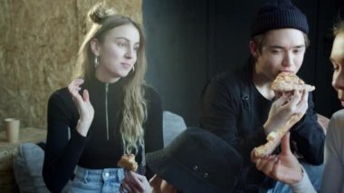 Genç dansçılar pizzanın son parçasını koltukta paylaşıyorlar.