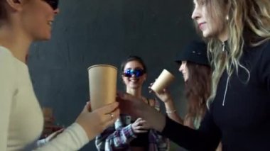 Siyah beyaz arka planda ellerinde kağıt bardaklarla dans eden bir grup genç. 