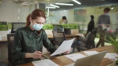 Çekici bir kadın çalışıyor ve belgelere bakıyor.