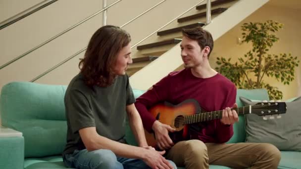 A két barát egyike gitározni próbál. — Stock videók